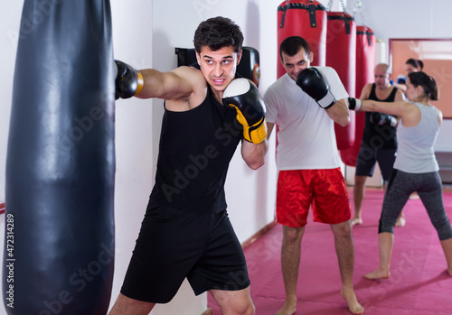 vigorous sportsman in the boxing hall practicing boxing punches with boxing bag during training