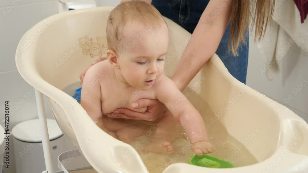 Cheerful smiling baby boy playing toys and splashing water in plastic children bath. Concept of children hygiene, healthcare and parenting. Cheerful smiling baby boy playing toys and splashing water in plastic children bath. Concept of children hygiene, healthcare and parenting.