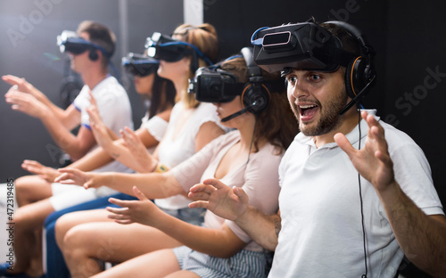 Excited young germany man experiencing with friends virtual reality