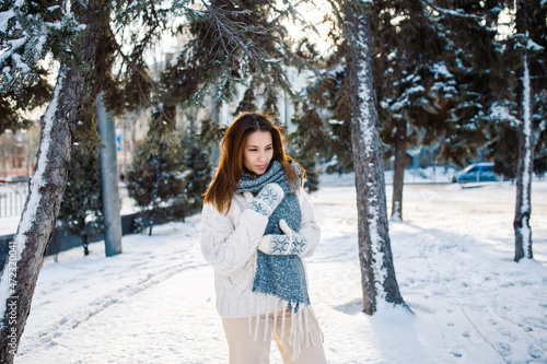 A beautiful woman walks in a winter park against the backdrop of snow-covered trees. Blur nature background.