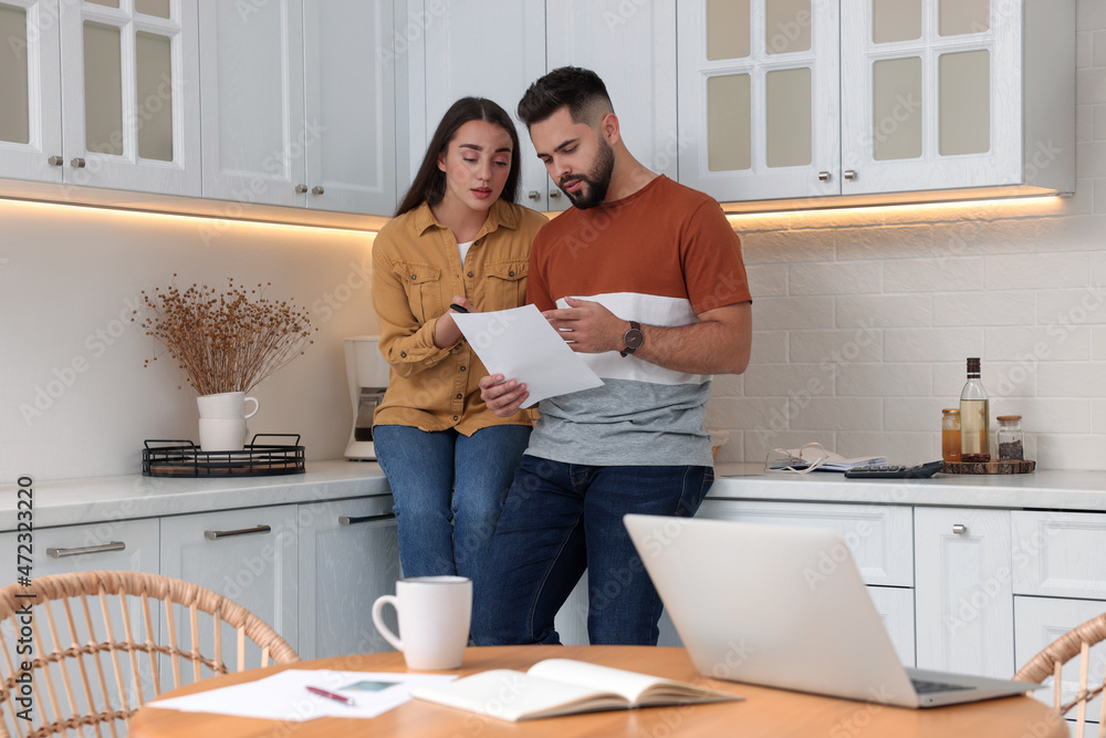 Young couple discussing family budget in kitchen Young couple discussing family budget in kitchen
