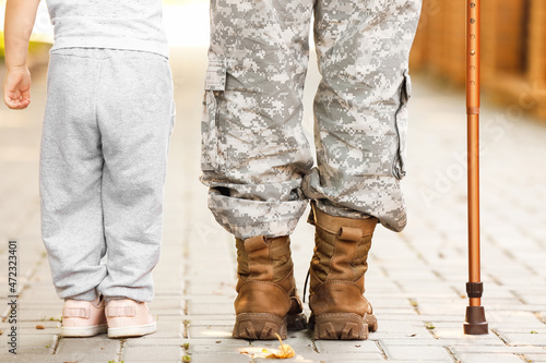 Female soldier with cane and her little daughter outdoors