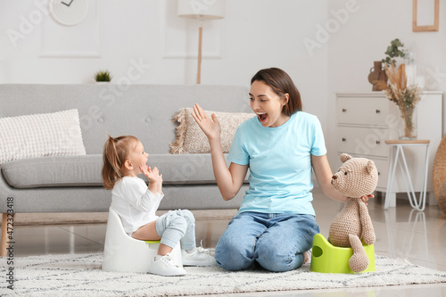 Mother potty training her little daughter at home photo