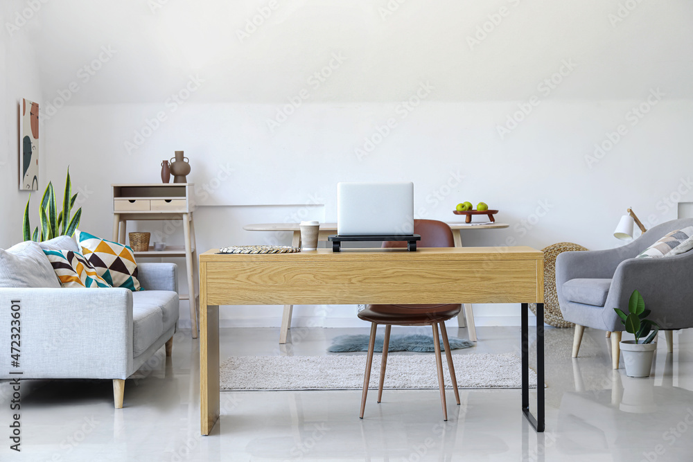 Wooden table with laptop and cup of coffee in interior of modern room Wooden table with laptop and cup of coffee in interior of modern room
