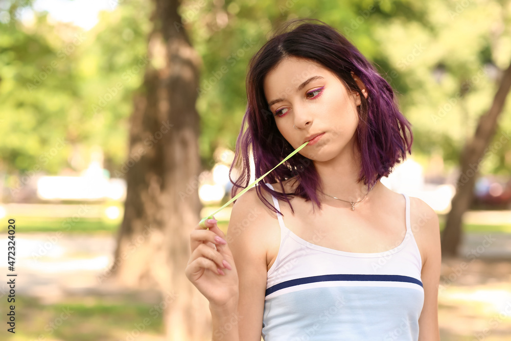 Young woman with purple hair chewing gum in park Young woman with purple hair chewing gum in park
