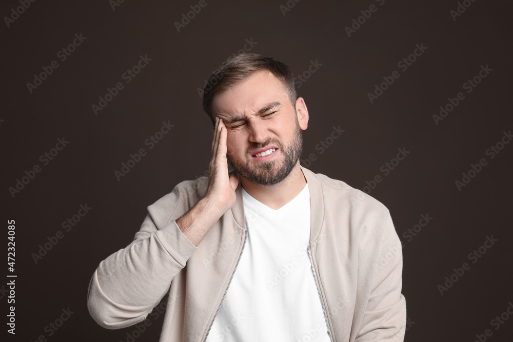 Young man suffering from headache on dark background Young man suffering from headache on dark background