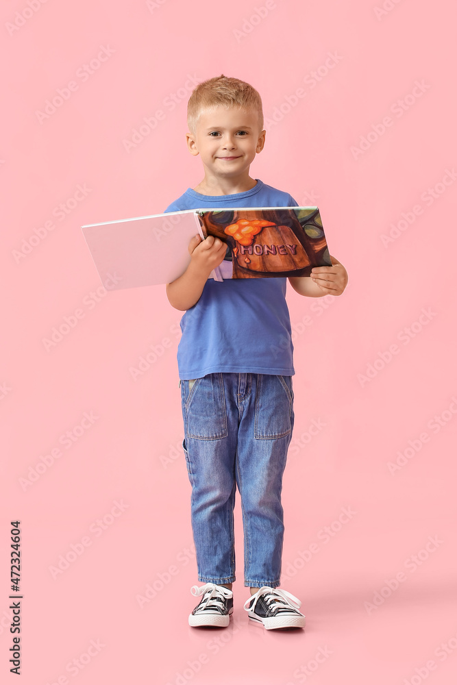 Adorable little boy with book on pink background Adorable little boy with book on pink background