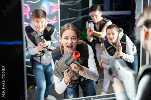Portrait of young woman with laser gun having fun on dark lasertag arena..