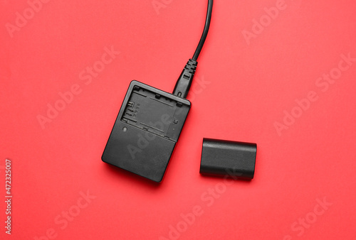Camera battery and charger on red background