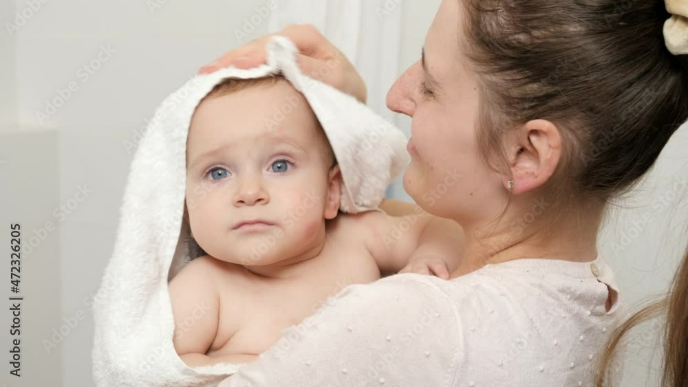 Caring mother wiping and drying her baby son with towel after washing in bath. Concept of children hygiene, healthcare and family care at home Caring mother wiping and drying her baby son with towel after washing in bath. Concept of children hygiene, healthcare and family care at home