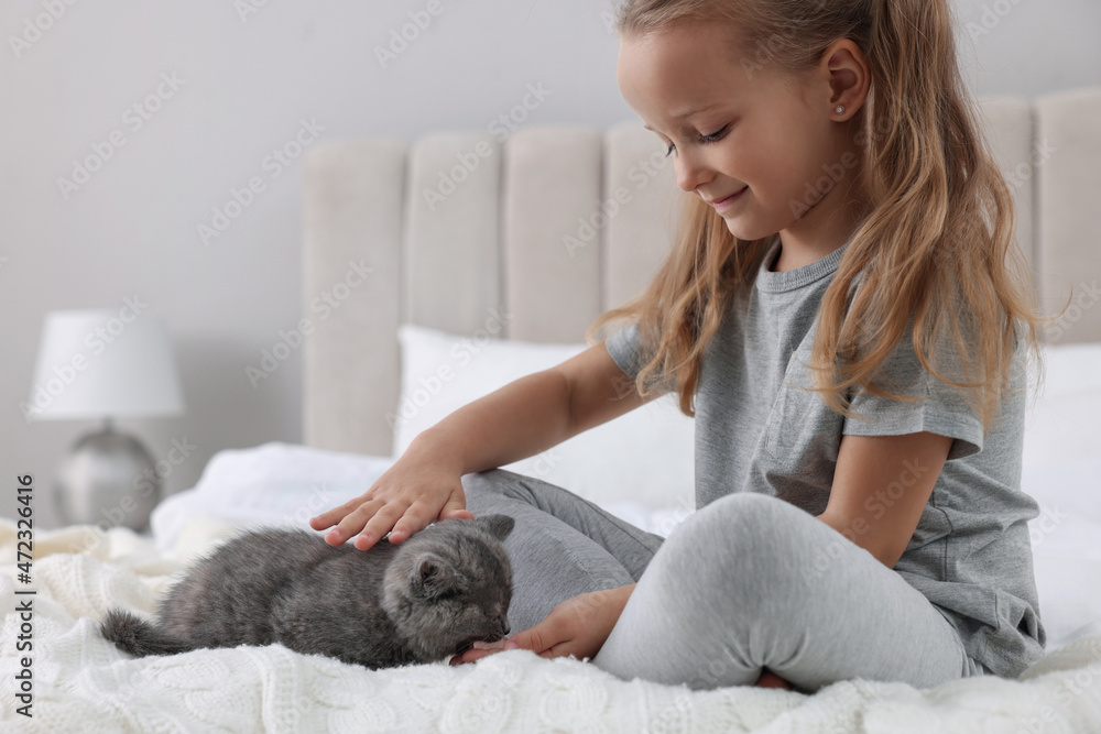 Cute little girl with kitten on bed at home. Childhood pet Cute little girl with kitten on bed at home. Childhood pet