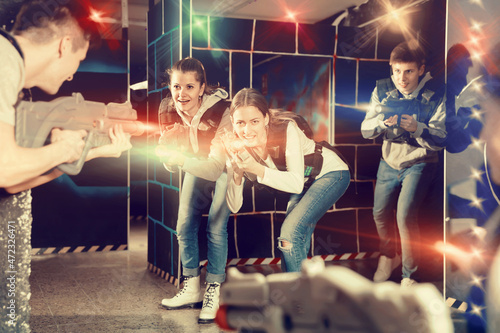 Young women with laser gun having fun on dark lasertag arena