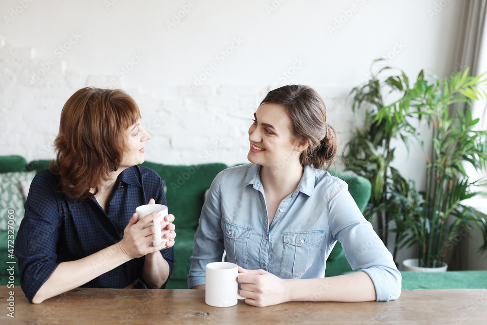 Beautiful mature mother and her adult daughter are drinking coffee Beautiful mature mother and her adult daughter are drinking coffee