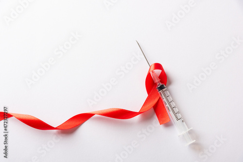 Фотография Red bow ribbon symbol HIV, AIDS cancer awareness and syringe with shadows, studi