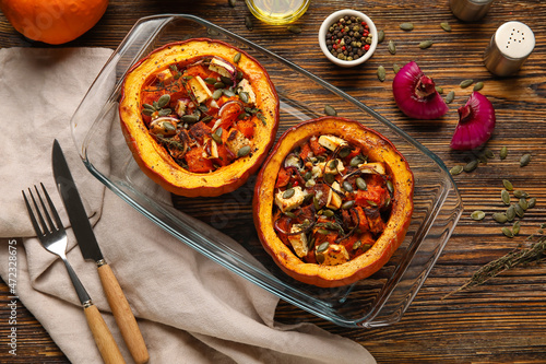 Baking dish with tasty stuffed pumpkins on wooden background