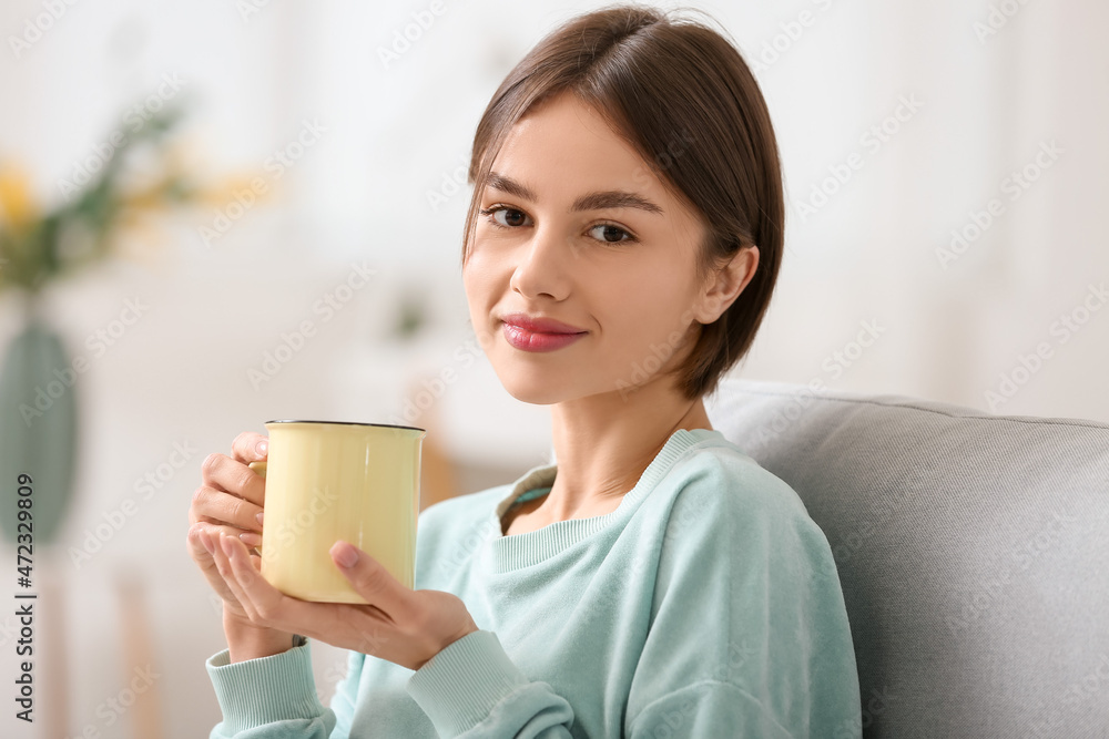 Beautiful young woman drinking tasty tea on sofa at home Beautiful young woman drinking tasty tea on sofa at home