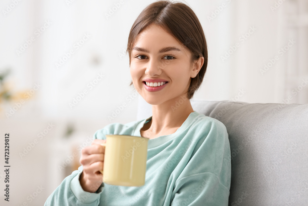 Beautiful young woman drinking tasty tea on sofa at home Beautiful young woman drinking tasty tea on sofa at home