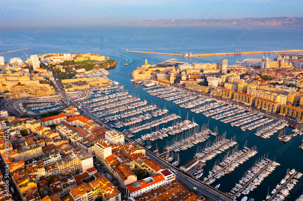 Picturesque drone view of modern Marseille cityscape on Mediterranean coast overlooking large Old Port with moored pleasure yachts on sunny day, France