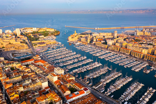 Picturesque drone view of modern Marseille cityscape on Mediterranean coast overlooking large Old Port with moored pleasure yachts on sunny day, France