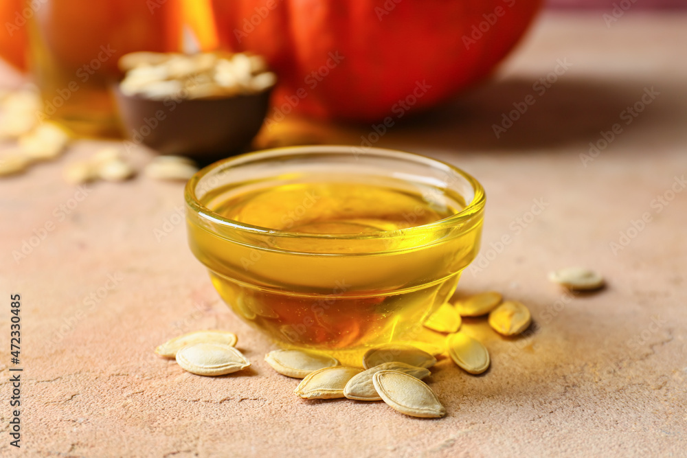 Bowl with pumpkin seed oil on beige background Bowl with pumpkin seed oil on beige background