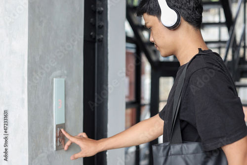 Asian young man pressing the elevator button