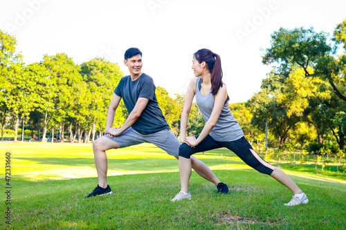 Asian male and female couple Exercise in the outdoor park in the morning. They are healthy, smiling and happy. fitness concept, health care