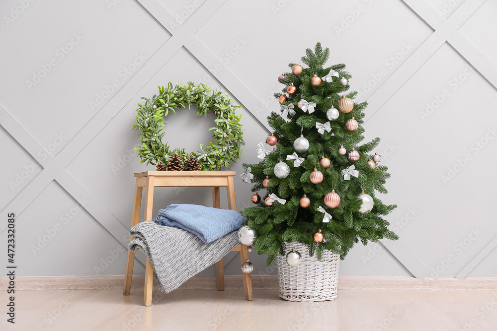 Beautiful Christmas tree and table with wreath near light wall Beautiful Christmas tree and table with wreath near light wall