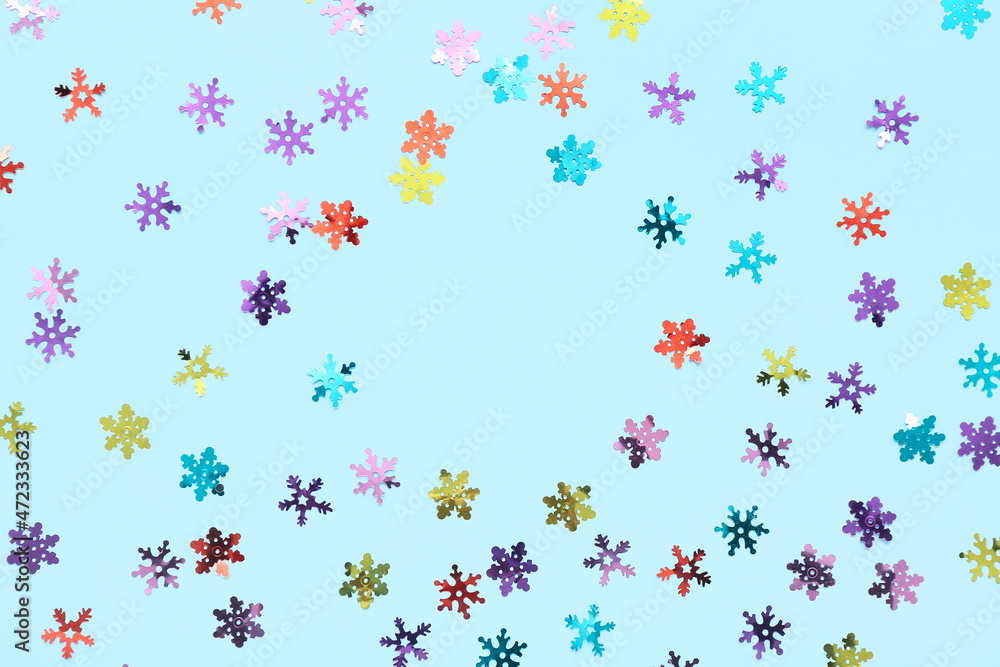 Frame made of confetti in shape of snowflakes on color background