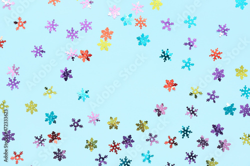Frame made of confetti in shape of snowflakes on color background