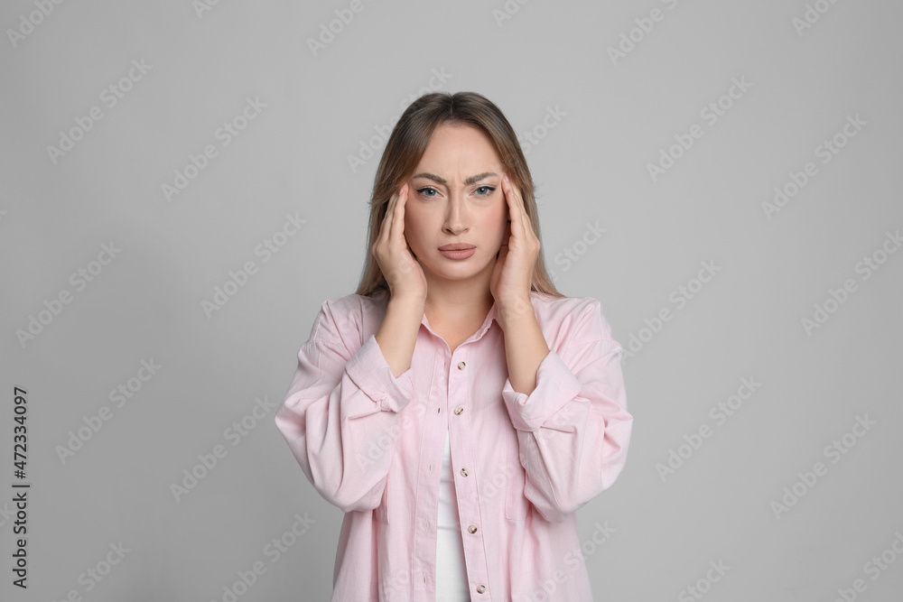 Young woman suffering from headache on light grey background Young woman suffering from headache on light grey background