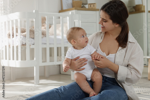 Happy young mother with her baby in nursery. Space for text