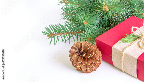 Close up red gift box and pine cone with green Christmas tree branches on white background. Copy space