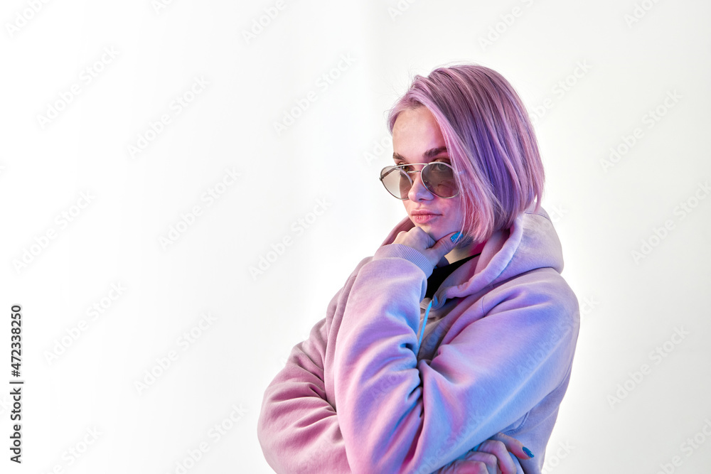 Serious young female in hoodie and stylish sunglasses touching chin and thinking over decision on white background Serious young female in hoodie and stylish sunglasses touching chin and thinking over decision on white background