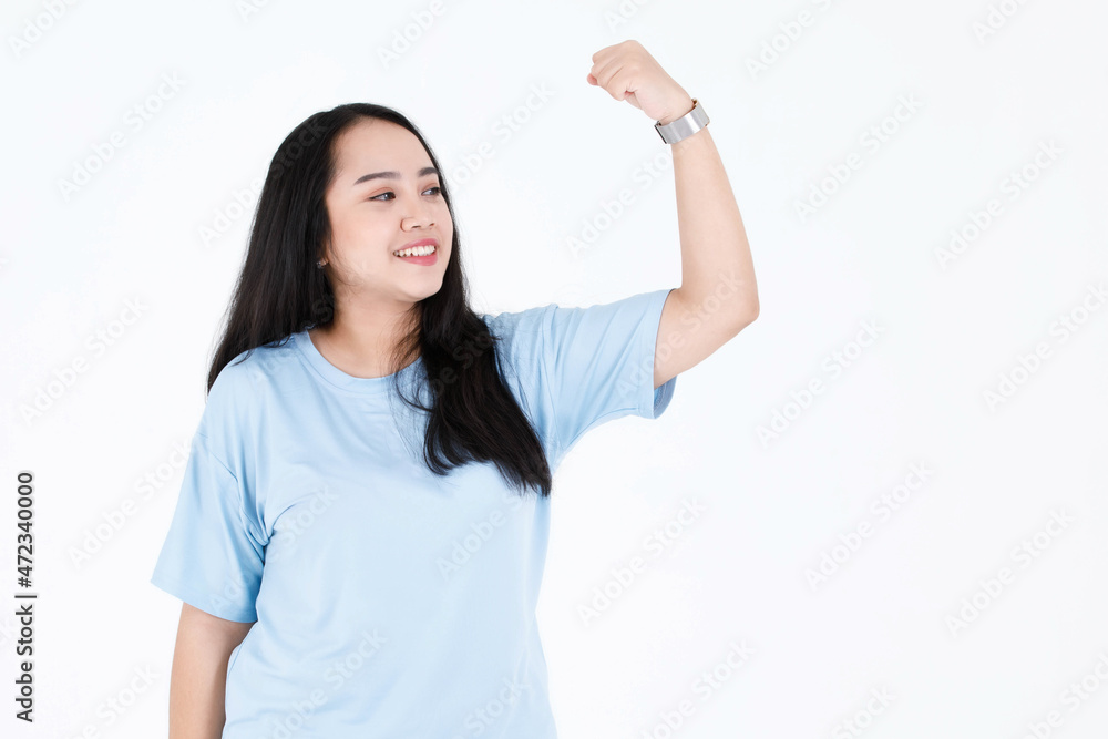Portrait studio shot of Asian chubby plump healthy long black hair female model in blue casual tshirt smiling look at camera showing biceps muscle strong muscular plus size body on white background Portrait studio shot of Asian chubby plump healthy long black hair female model in blue casual tshirt smiling look at camera showing biceps muscle strong muscular plus size body on white background