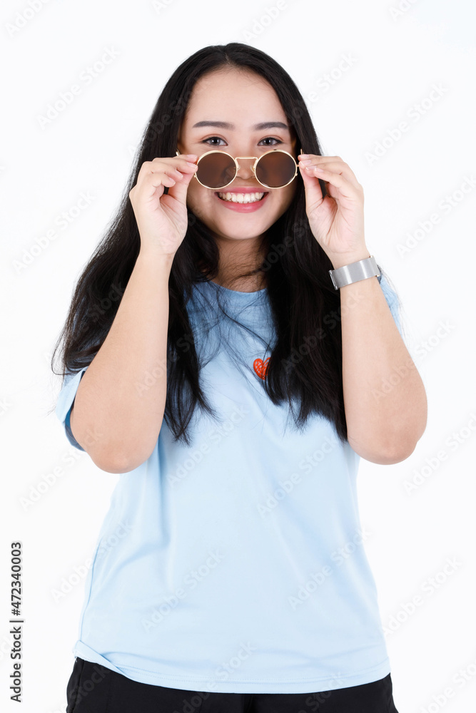 Portrait studio shot of Asian chubby plump healthy long black hair female model in blue casual shirt standing smiling look at camera holding touching take off vintage sunglasses on white background Portrait studio shot of Asian chubby plump healthy long black hair female model in blue casual shirt standing smiling look at camera holding touching take off vintage sunglasses on white background