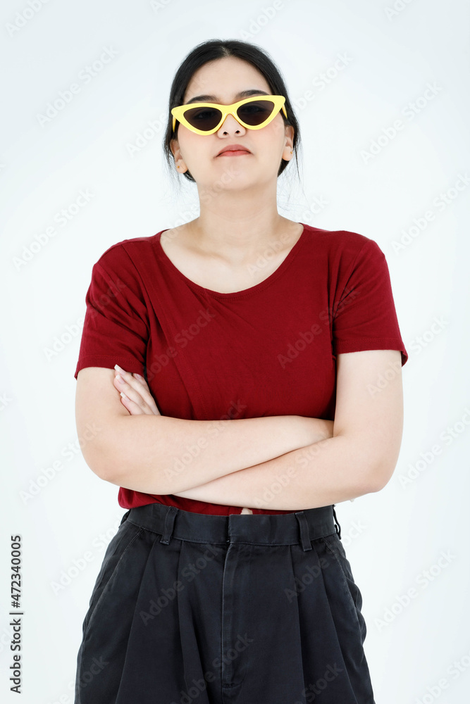 Portrait studio shot of Asian young cool fashionable stylish ponytail hairstyle female model in casual outfit wear yellow fashion sunglasses standing crossed arms look at camera on white background Portrait studio shot of Asian young cool fashionable stylish ponytail hairstyle female model in casual outfit wear yellow fashion sunglasses standing crossed arms look at camera on white background