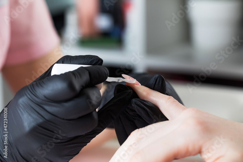 Manicure process in a beauty salon. The manicurist paints the nail with varnish.