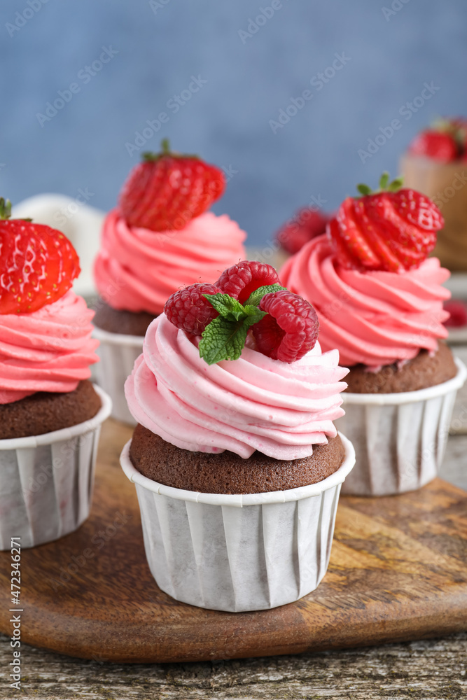 Sweet cupcakes with fresh berries on wooden table, closeup