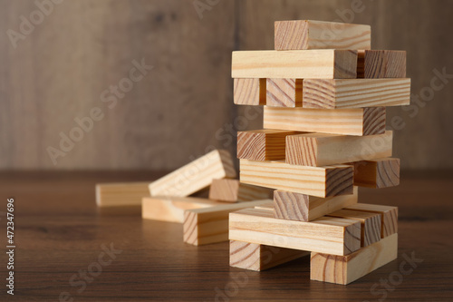 Jenga tower and wooden blocks on table, space for text photo