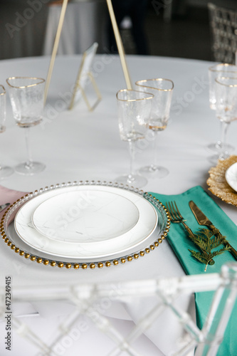 Beautiful festive table setting with napkins of different colors. A luxurious dining set with cutlery, napkin, dishes and covered with a tablecloth in the restaurant. Gold plates and crystal glasses. 