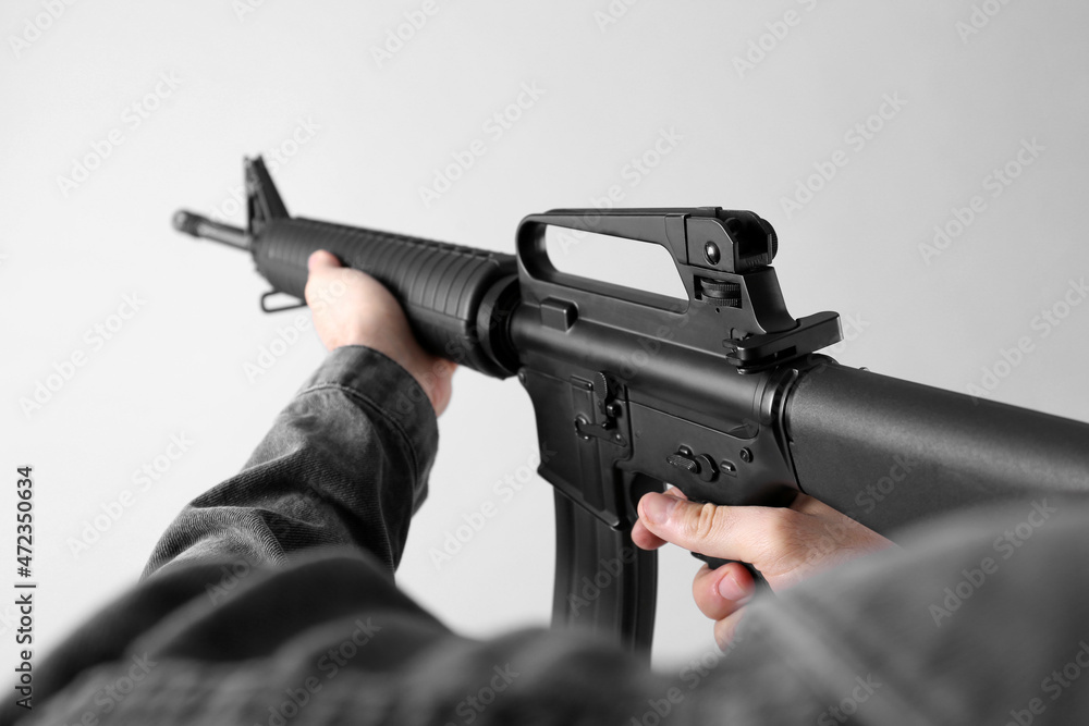 Assault gun. Man aiming rifle on light background, closeup Assault gun. Man aiming rifle on light background, closeup