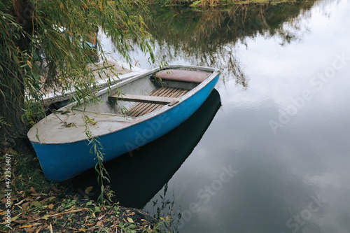 Fototapeta Naklejka Na Ścianę i Meble -  Light blue wooden boat on lake near pier, space for text
