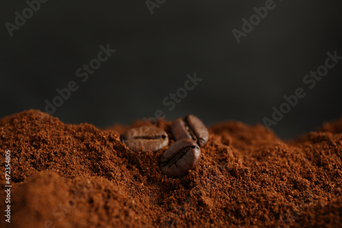 Coffee grounds and roasted beans on dark background, closeup photo