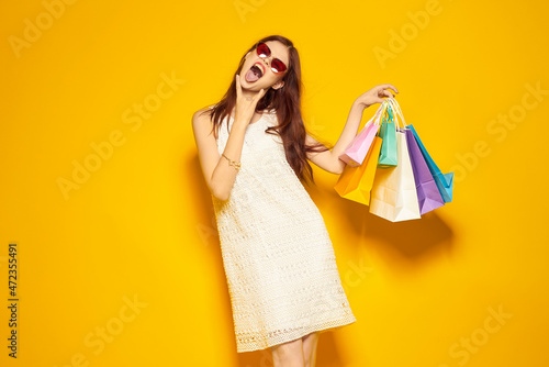smiling woman with packages in hands Shopaholic yellow background