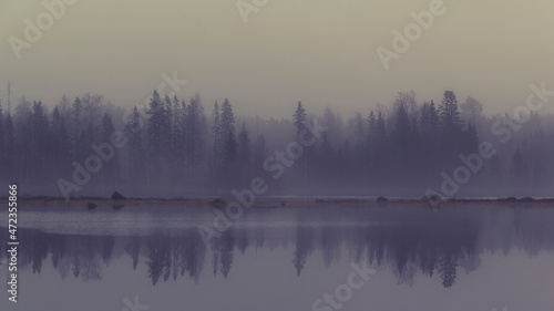 Fog and gray weather where the bay's opposite shoreline is reflected in Ytterbodafjärden's water level.