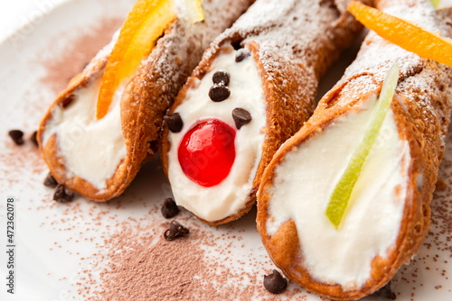 Cannoli siciliani, deliziosi dessert tipici della cucina Italiana farciti con crema di ricotta, frutta candita e gocce di cioccolato  photo