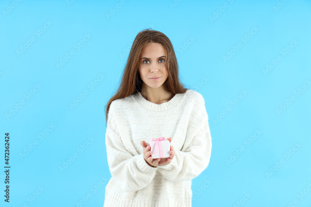 Attractive woman holds gift box on blue background Attractive woman holds gift box on blue background