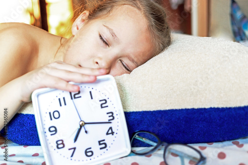 Obraz na plátně Girl sleeping on a pillow with an alarm clock in hand resting in the morning