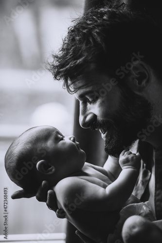 Φωτογραφία Stylish Caucasian bearded father carrying newborn baby on shoulder