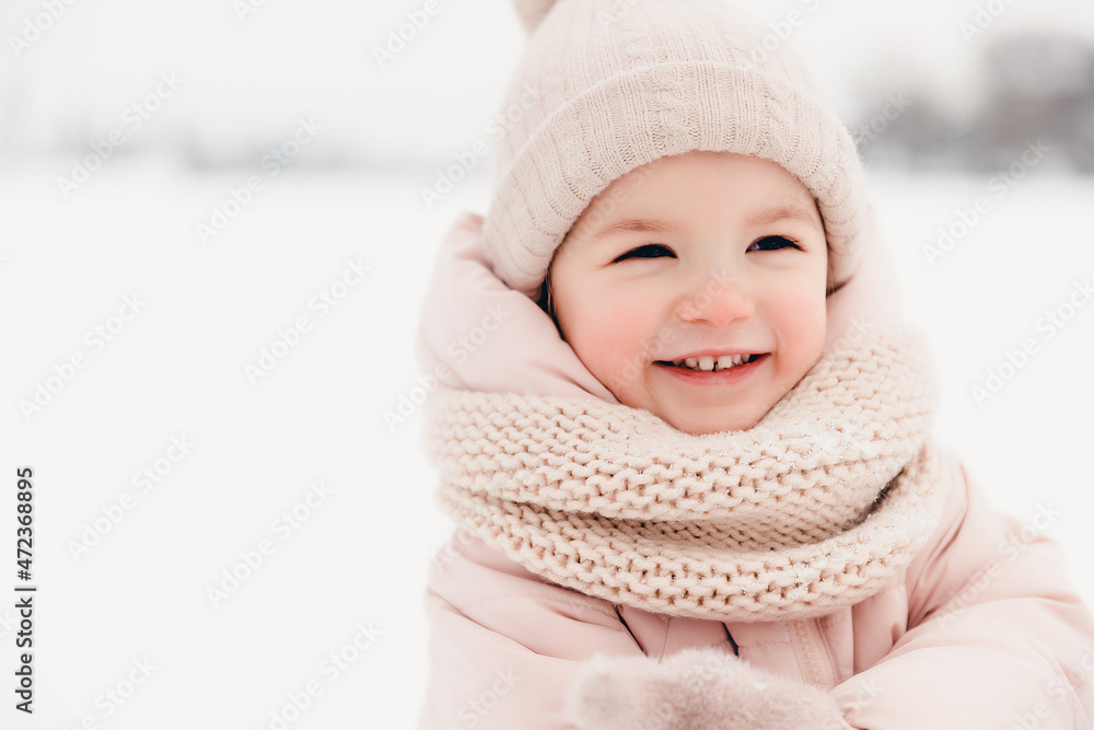 Happy laughing girl wearing a pink jacket, scarf and hat, playing in a beautiful snowy winter walk. Girl enjoys winter, frosty day. Playing with snow on winter holidays. Winter holidays concept. Happy laughing girl wearing a pink jacket, scarf and hat, playing in a beautiful snowy winter walk. Girl enjoys winter, frosty day. Playing with snow on winter holidays. Winter holidays concept.